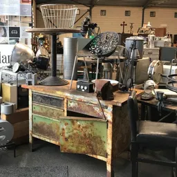 Winkelvloer met verzameling vintage voorwerpen, oude gereedschappen en gebruiksartikelen op houten tafel en planken