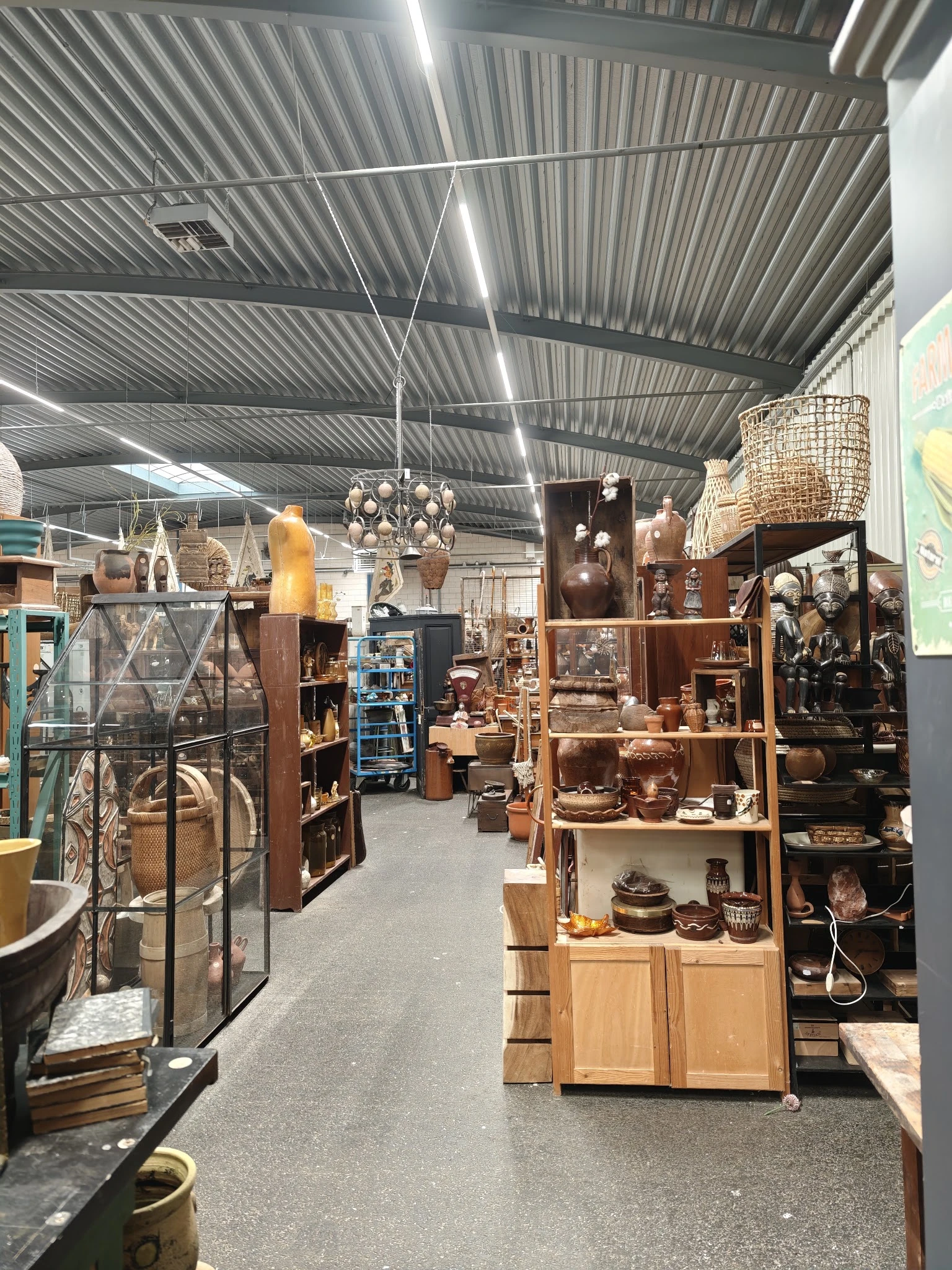 Overzicht van de winkelvloer met diverse stellingen, meubels, lampen en decoratieve items in een kringloopwinkel