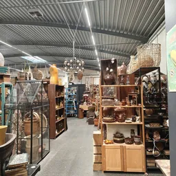 Overzicht van de winkelvloer met diverse stellingen, meubels, lampen en decoratieve items in een kringloopwinkel