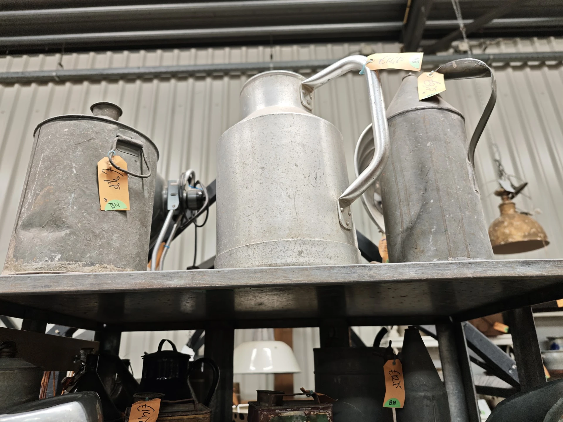 Vintage tinnen kannen en metalen huishoudartikelen op een plank in een kringloopwinkel