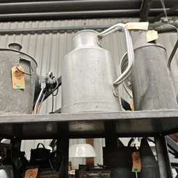 Vintage tinnen kannen en metalen huishoudartikelen op een plank in een kringloopwinkel