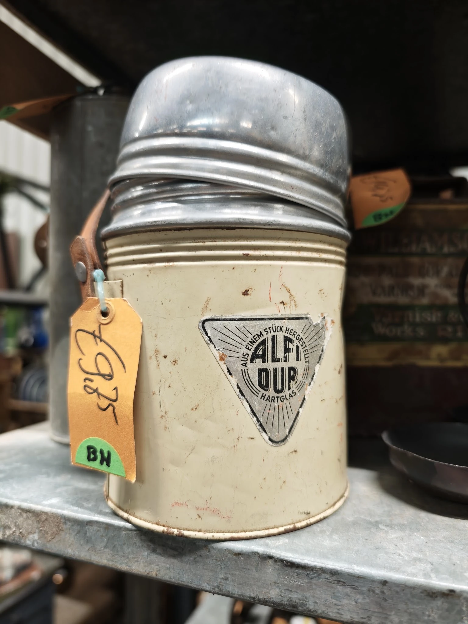 Glazen pot met witte inhoud en metalen deksel, voorzien van geel prijskaartje met 'BH' markering