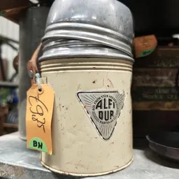 Glazen pot met witte inhoud en metalen deksel, voorzien van geel prijskaartje met 'BH' markering