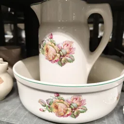 Wit porselein servies met roze bloemenpatroon, bestaande uit kan en kom