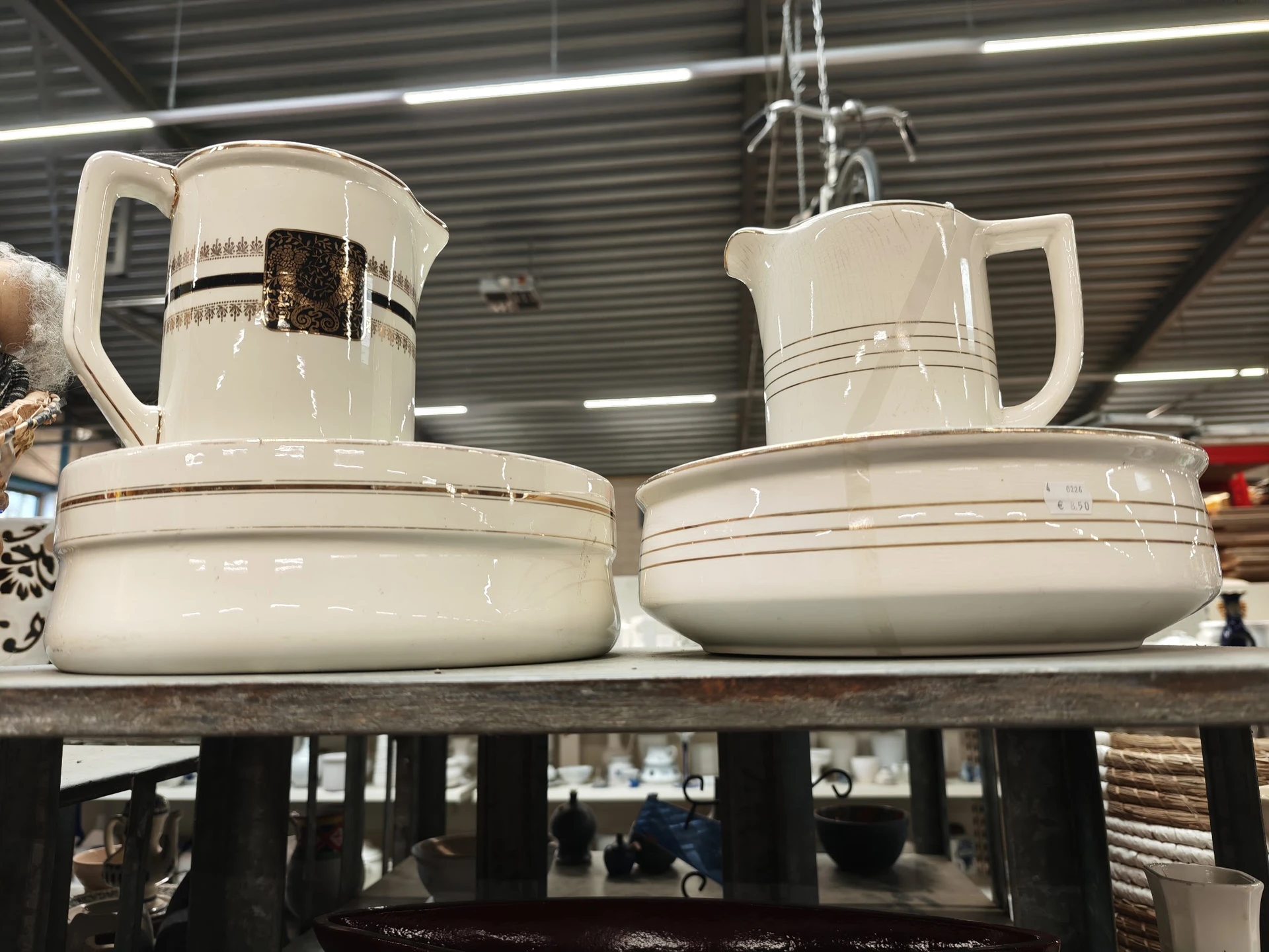 Twee witte porseleinen koffiekannen en schotels op een plank in de winkel