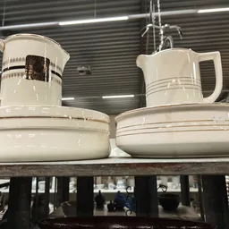 Twee witte porseleinen koffiekannen en schotels op een plank in de winkel