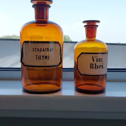 Twee antieke apothekersflesjes met amber glas en labels voor Thymi en Vini Rhei