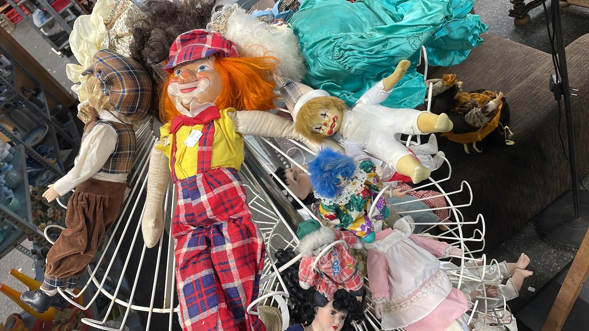 Verzameling vintage speelgoed en poppen op de grond, waaronder clowns en poppenkleding