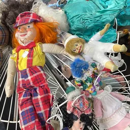 Verzameling vintage speelgoed en poppen op de grond, waaronder clowns en poppenkleding