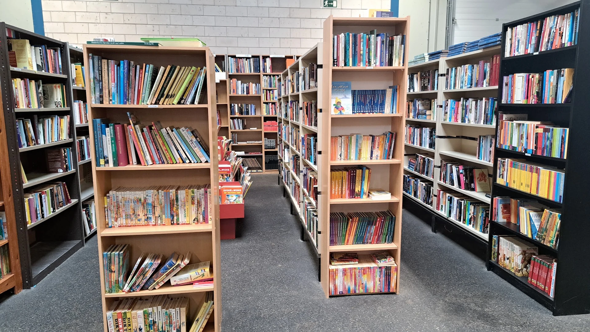 Boekenrekken met dvd's en boeken in een kringloopwinkel