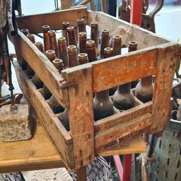 Houten kratje met bruine glazen flesjes, vintage flessenrek