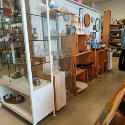 Winkelvloer met houten kasten, vitrines met keramiek en decoratieve items, klanten in de winkel
