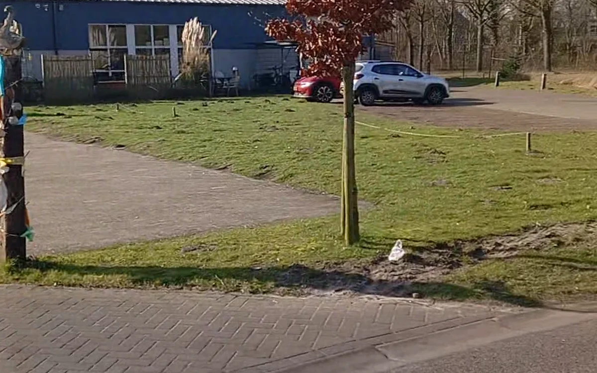 Blauwe winkelgevel met parkeerplaats en geparkeerde auto's op het terrein