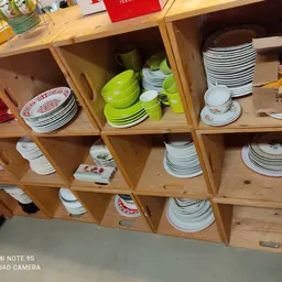Houten stellingkast met servies, borden, kopjes en keukengerei in diverse kleuren en patronen