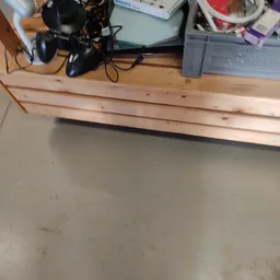Betonnen vloer met houten planken tegen een muur, gaming-apparatuur bovenop