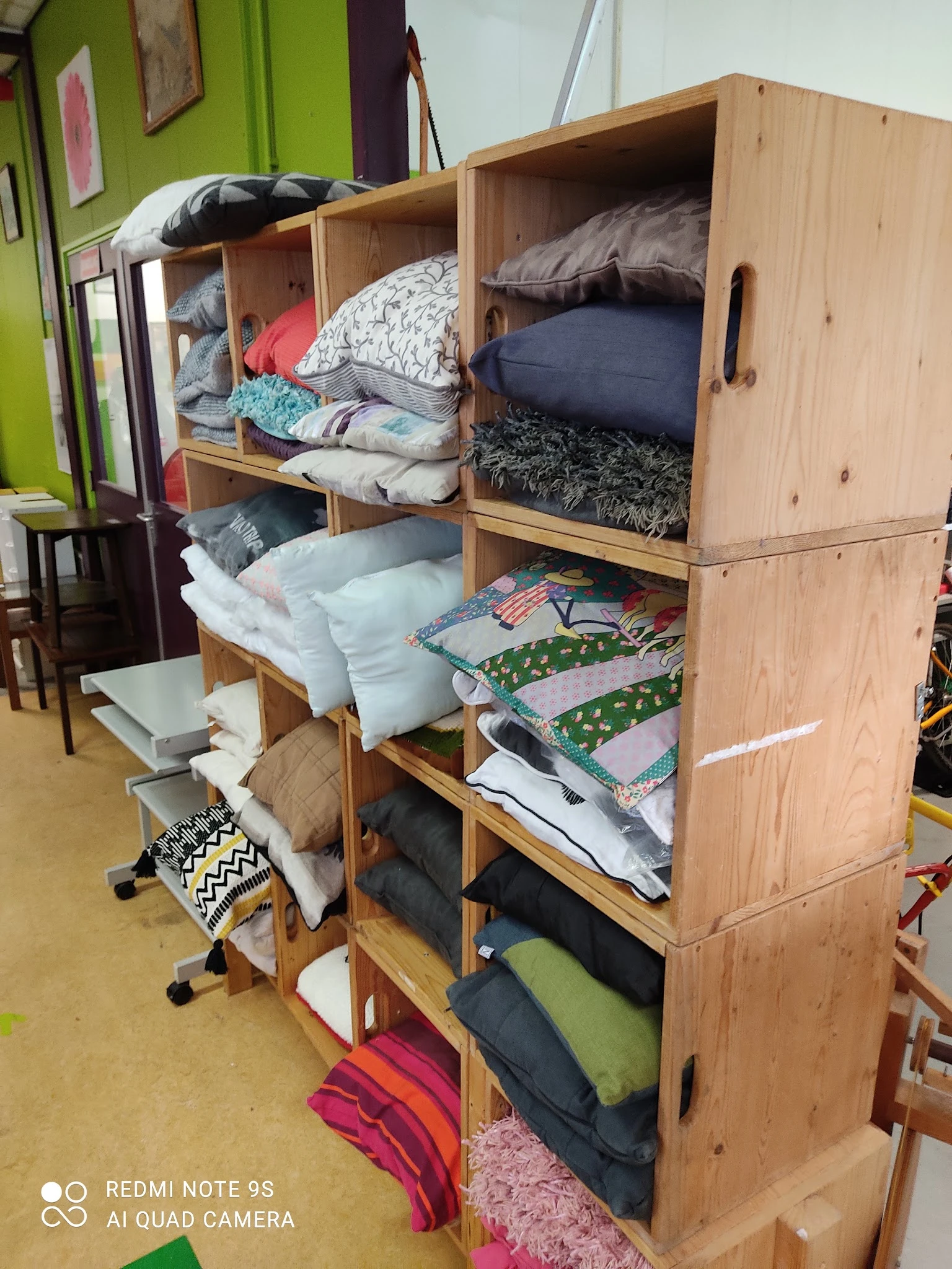 Houten kastunit gevuld met stapels bedengoed, kussens en textiel