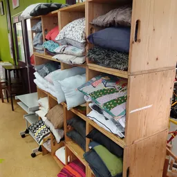 Houten kastunit gevuld met stapels bedengoed, kussens en textiel