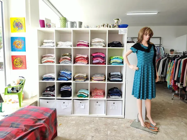 Interieur van tweedehandswinkel met kastruimte, kledingrekken en etalagepop in turquoise jurk