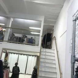 Bovenaanzicht van een kringloopwinkel met trappenhuizen, stellingen en fluorescente verlichting