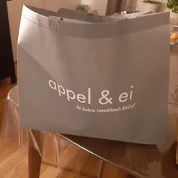Witte plastic tas met logo en tekst 'appel & ei - De leukste tweedehandskleding!'