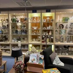 Vitrinekast vol met porselein, serviesgoed en decoratieve objecten in een kringloopwinkel