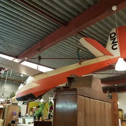 Plafond met rode balken en hangend zeilschip model in een kringloopwinkel