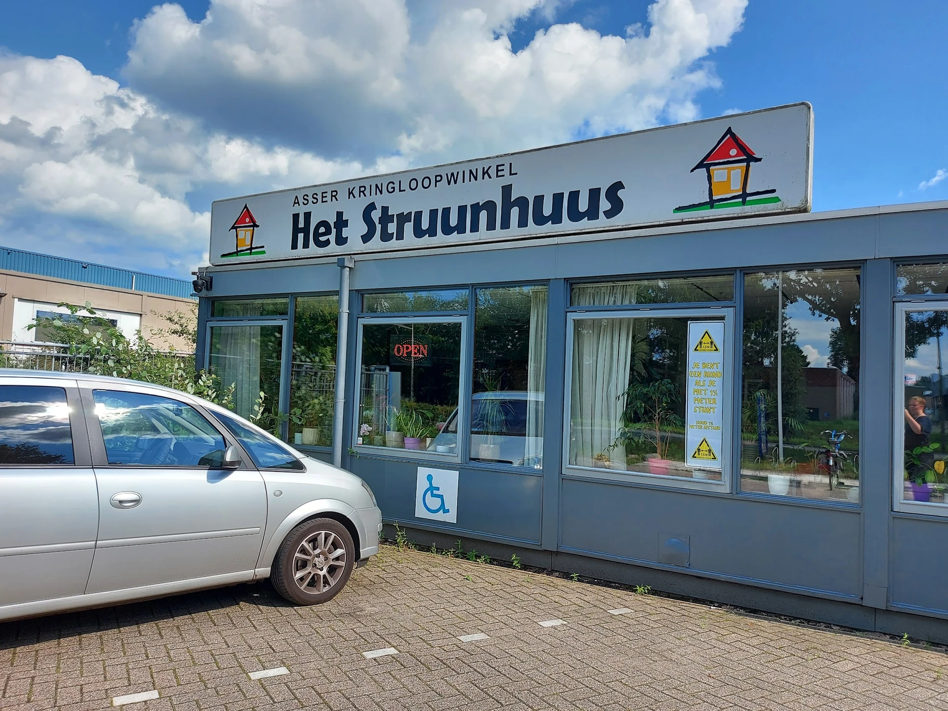 Blauwe gevel van kringloopwinkel Het Struunhuus met winkelnaam op bord, vitrine en ingang zichtbaar