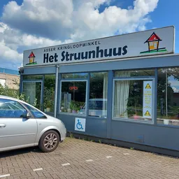 Blauwe gevel van kringloopwinkel Het Struunhuus met winkelnaam op bord, vitrine en ingang zichtbaar