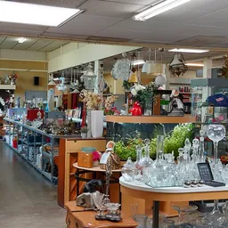 Winkelvloer van kringloopwinkel met glazen vitrines, houten toonbanken en diverse uitgestalde spullen