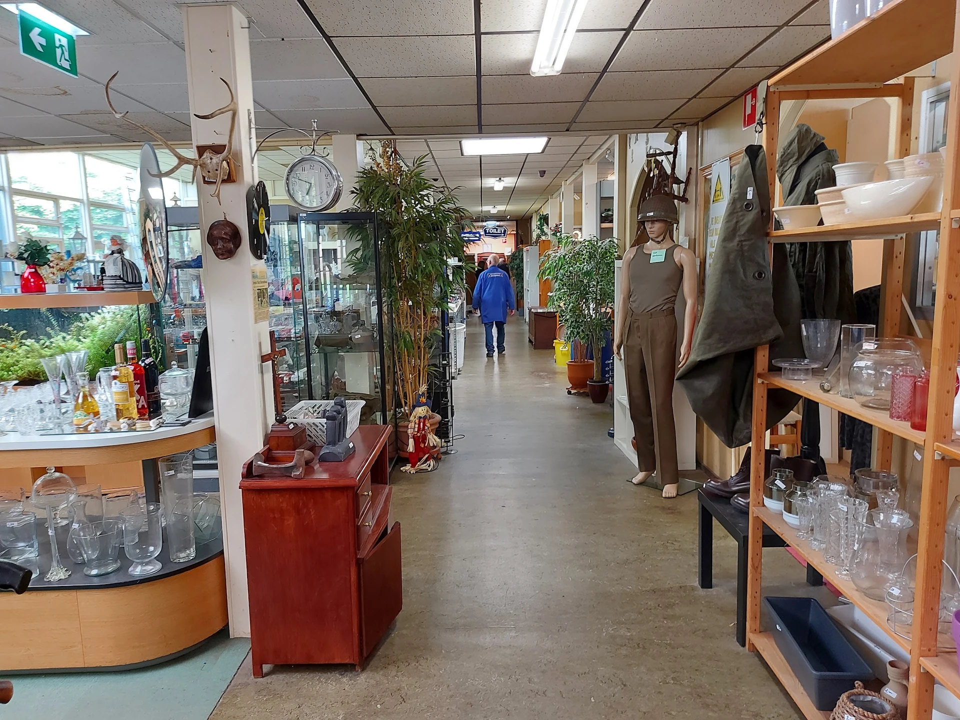 Winkelvloer met stellingen, toonbanken en diverse spullen in kringloopwinkel