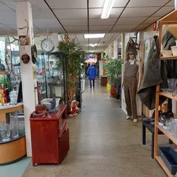 Winkelvloer met stellingen, toonbanken en diverse spullen in kringloopwinkel