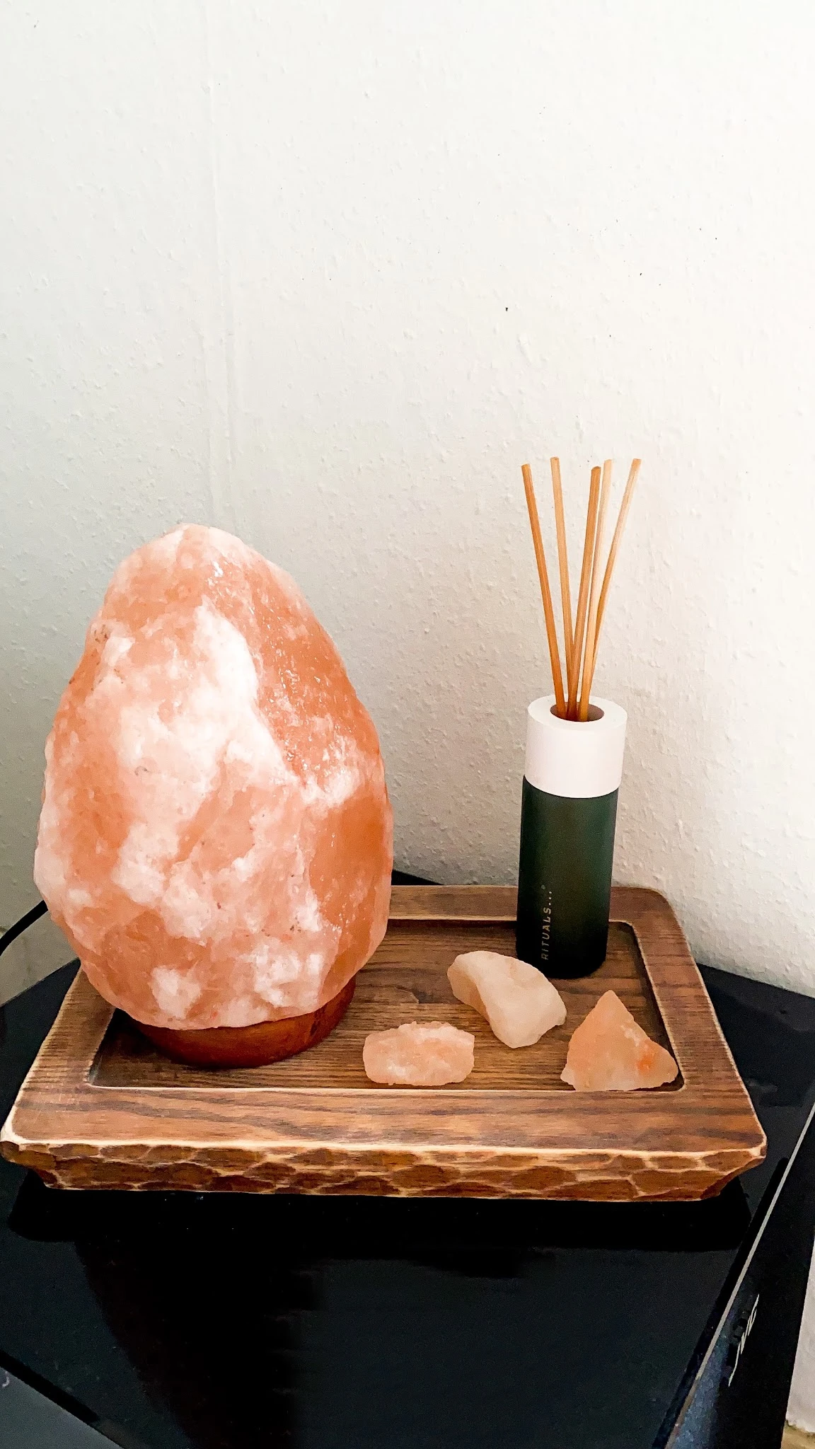 Himalayazoutsteen lamp, geurstokjes in fles en decoratieve stenen op houten oppervlak