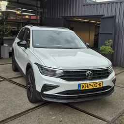 Witte Volkswagen SUV geparkeerd voor het bedrijf, frontaanzicht met zichtbare VW-grille en Nederlands kenteken