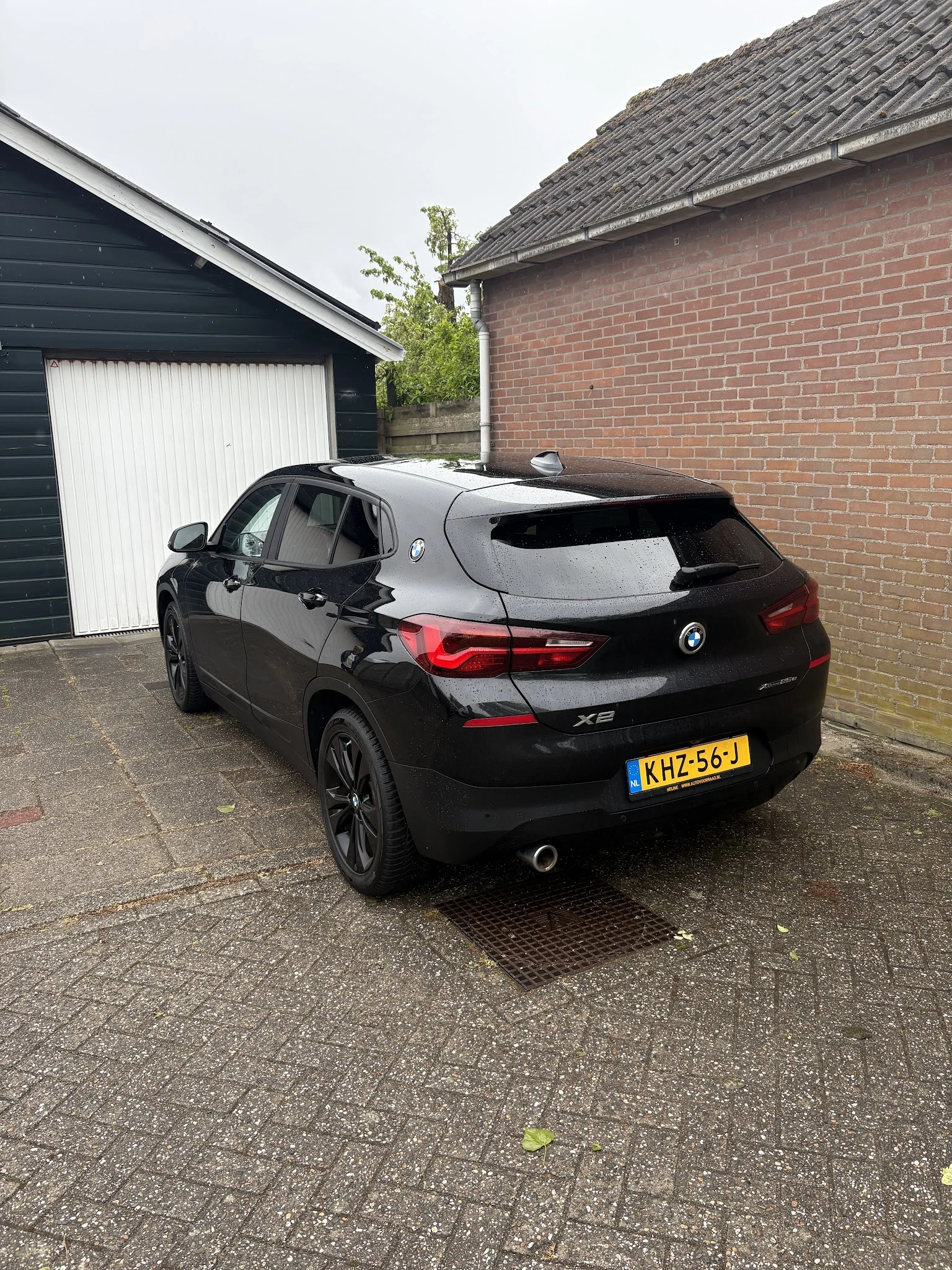 Zwarte BMW X2 geparkeerd op oprit naast garage