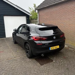 Zwarte BMW X2 geparkeerd op oprit naast garage