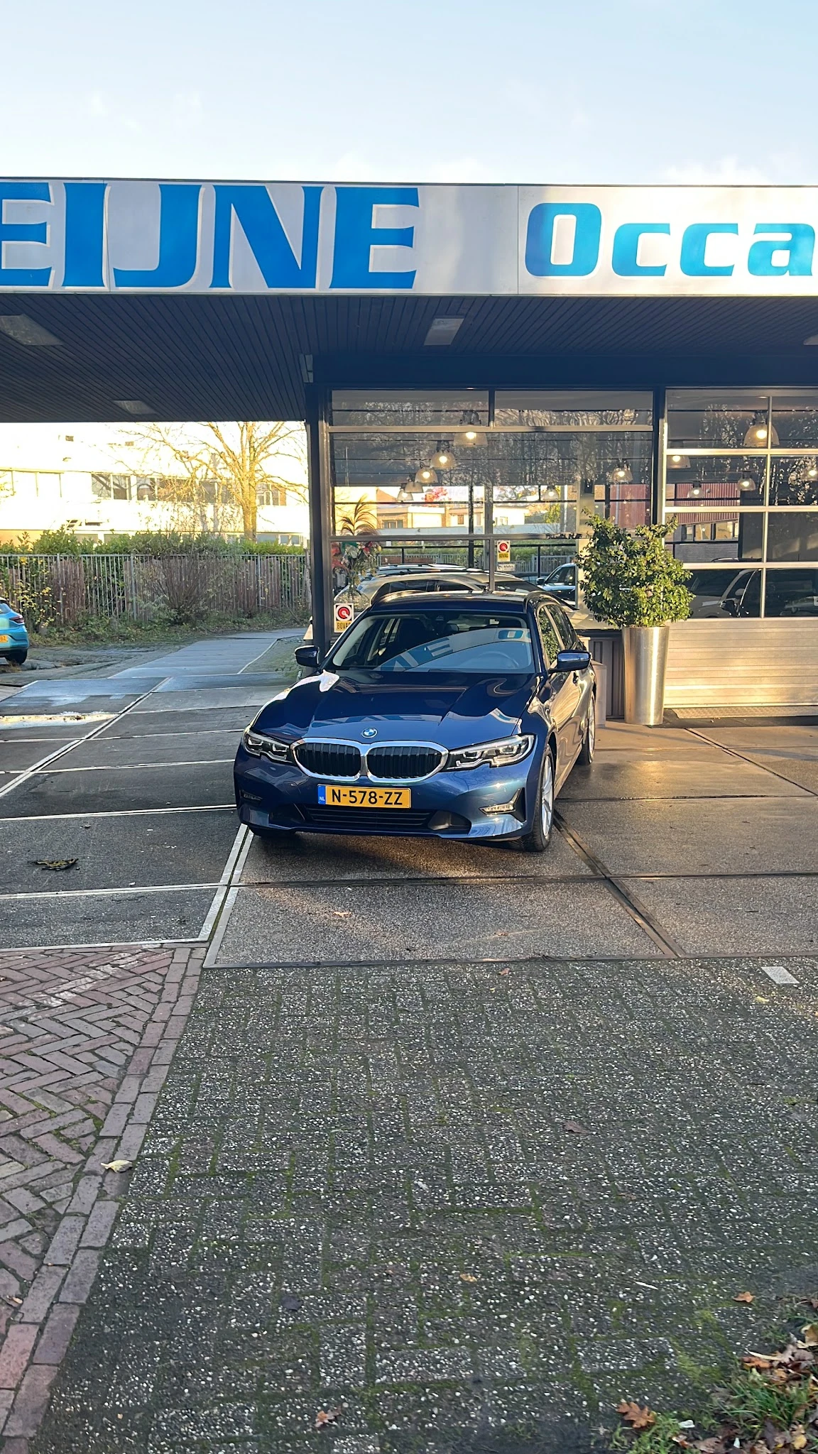 Blauwe BMW-auto geparkeerd voor de gevel van autobedrijf Heijne