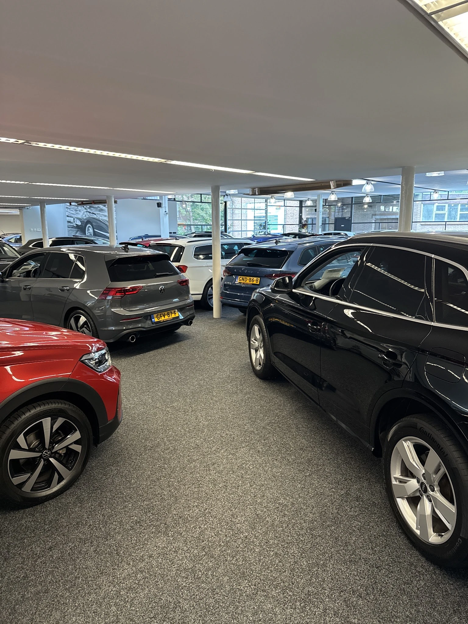 Showroom met meerdere geparkeerde auto's onder fluorescente verlichting