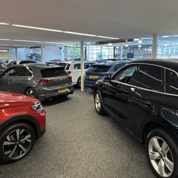 Showroom met meerdere geparkeerde auto's onder fluorescente verlichting