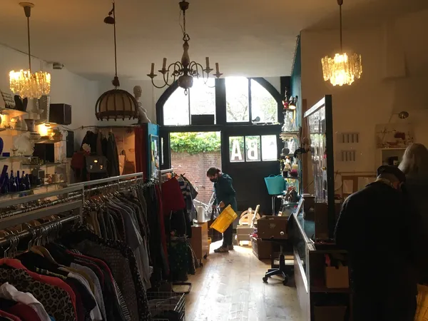 Winkelinterieur met kledingrekken, hanglampen en grote ramen met uitzicht op straat