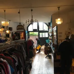 Winkelinterieur met kledingrekken, hanglampen en grote ramen met uitzicht op straat