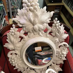 Decoratieve witte spiegel met barokke bloemenmotieven op rode ondergrond