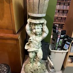Stenen decoratief beeldhouwwerk van een cherubijn of kinderhoofdje als bloemenpot, grijs-groen gepatineerd.