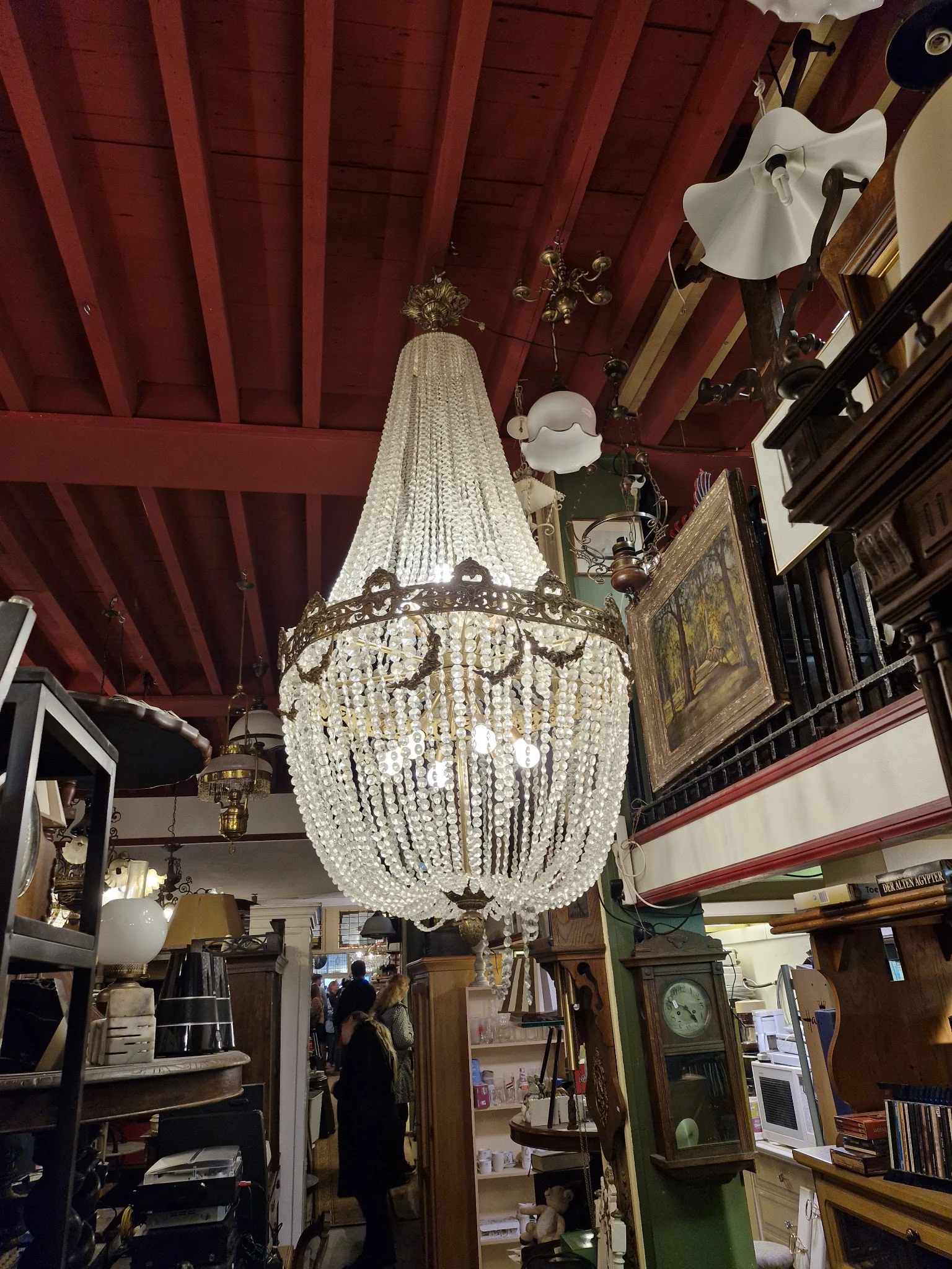 Kristallen kroonluchter met kralen hangers, ophangbaar aan een rood plafond