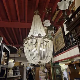 Kristallen kroonluchter met kralen hangers, ophangbaar aan een rood plafond