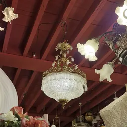 Kristallen kroonluchter met goudkleurig ornament aan rood houten plafond