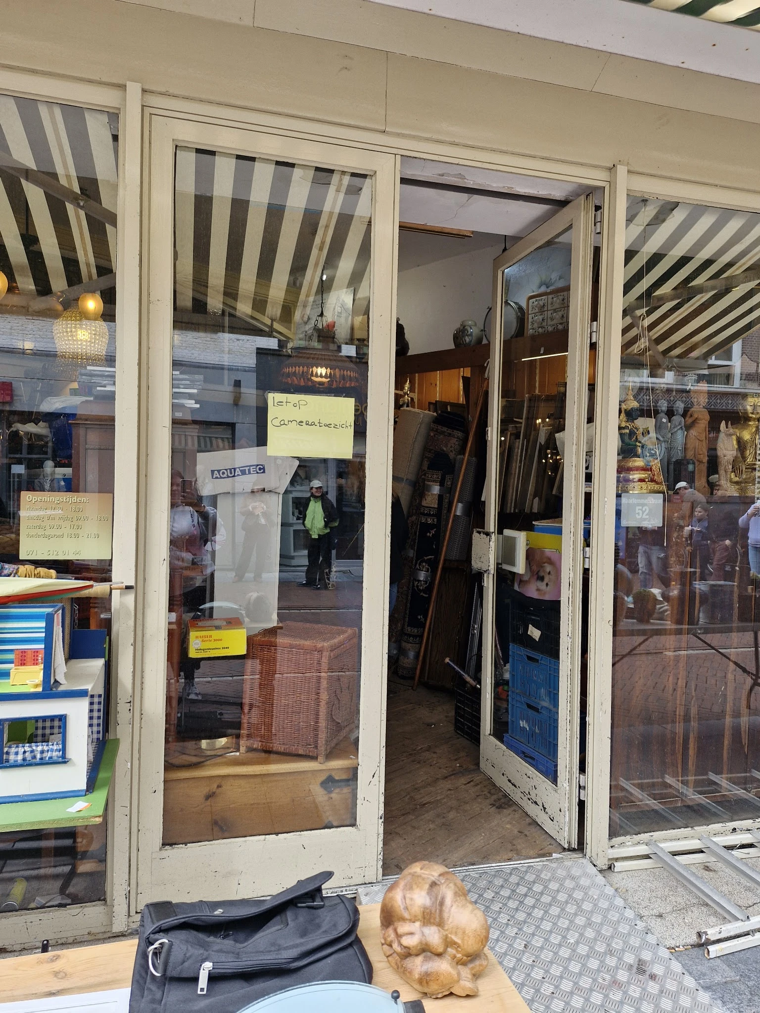 Winkelfront met glazen deuren en ramen, gedeeltelijk zichtbaar met straatreflecties en gele notities op glas