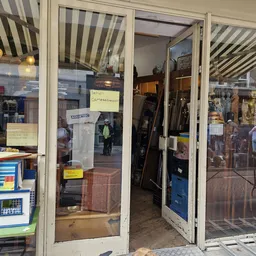 Winkelfront met glazen deuren en ramen, gedeeltelijk zichtbaar met straatreflecties en gele notities op glas