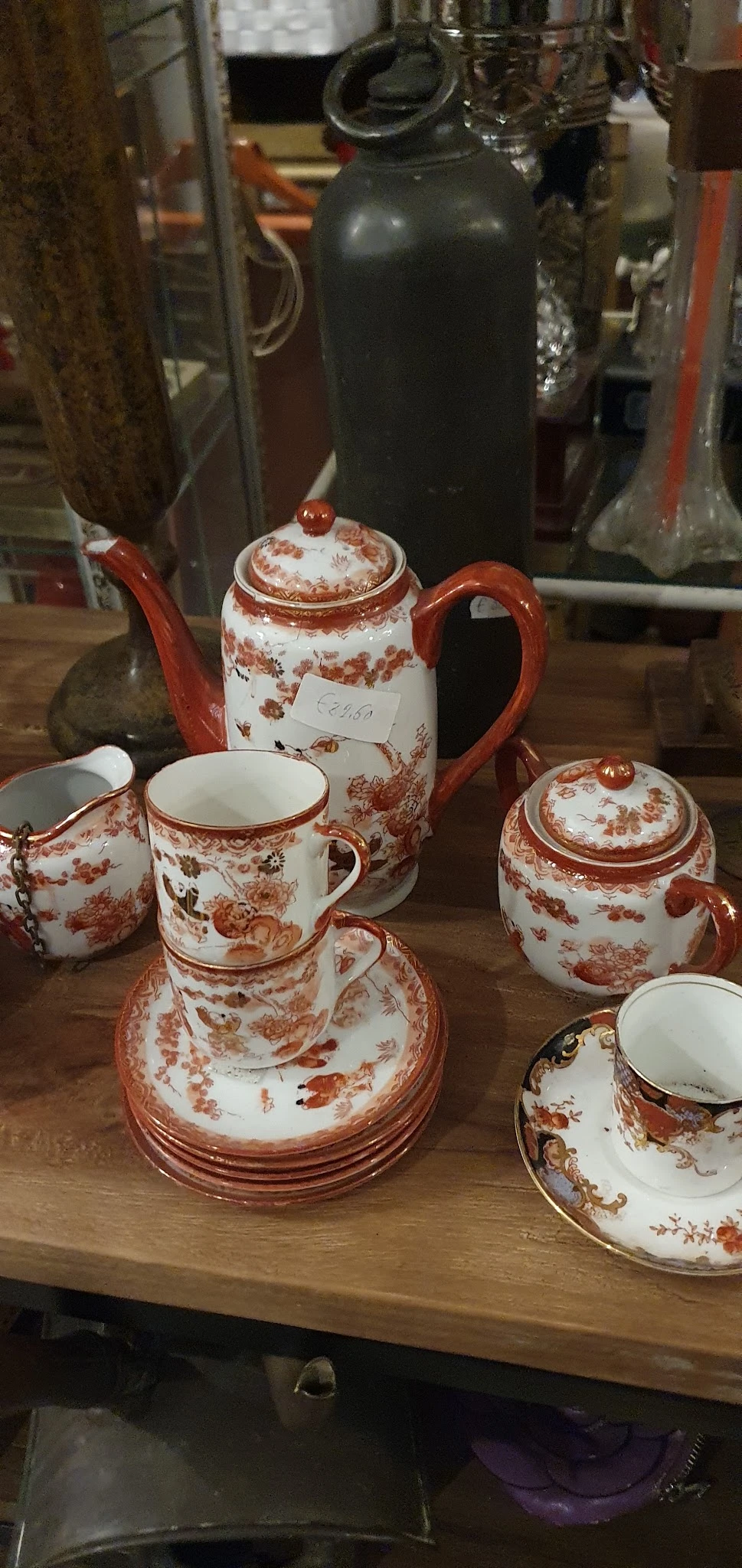 Rood en wit porseleinservies met bloemenpatroon: theepot, kopjes, schoteltjes en suikerpot.