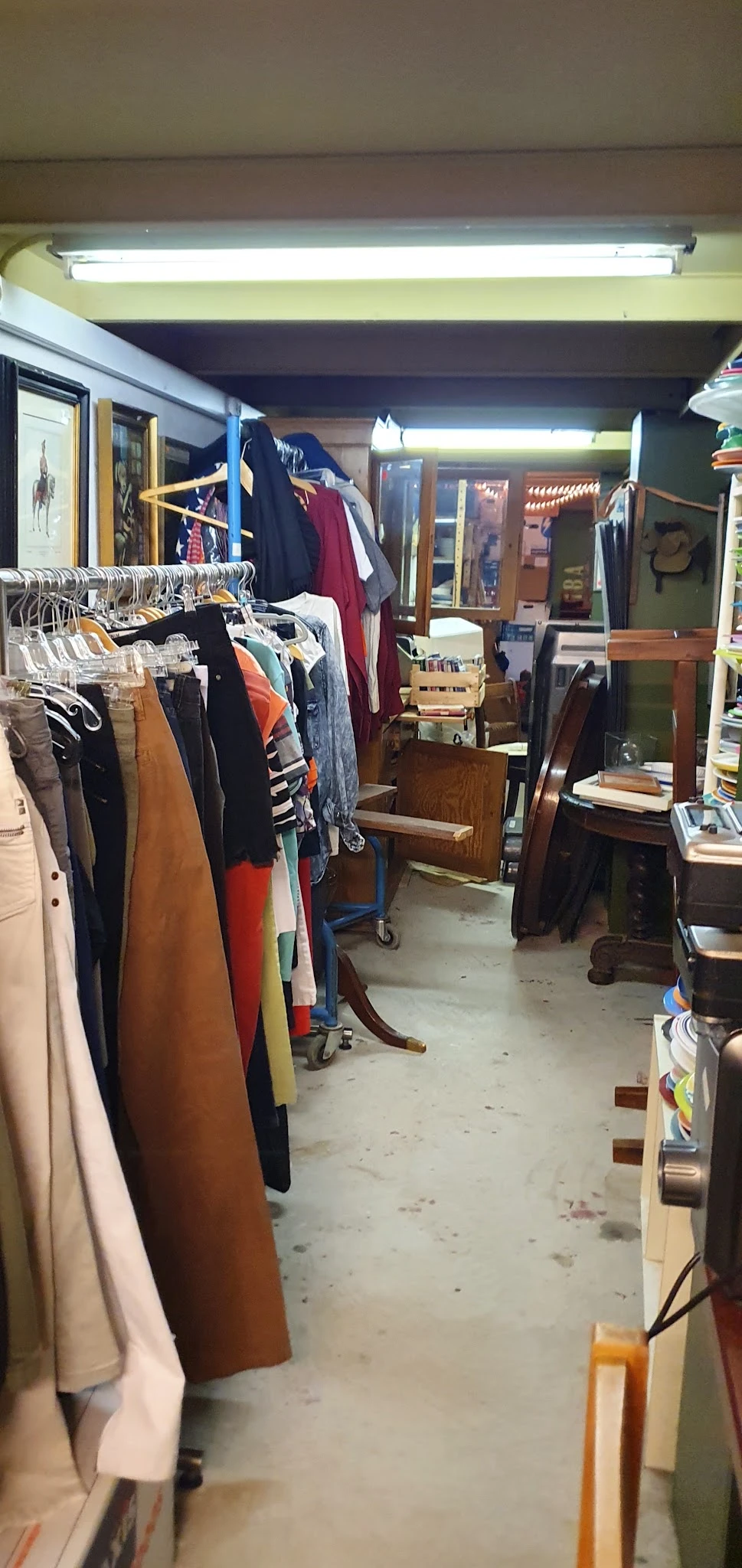 Winkelvloer met kledingrekken vol tweedehands kleding, houten meubels en diverse spullen