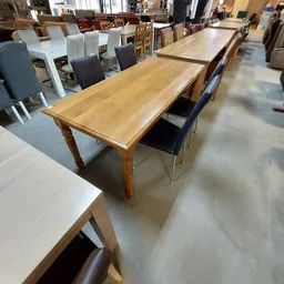 Houten eettafel met getorneerde poten en twee stoelen in de winkel